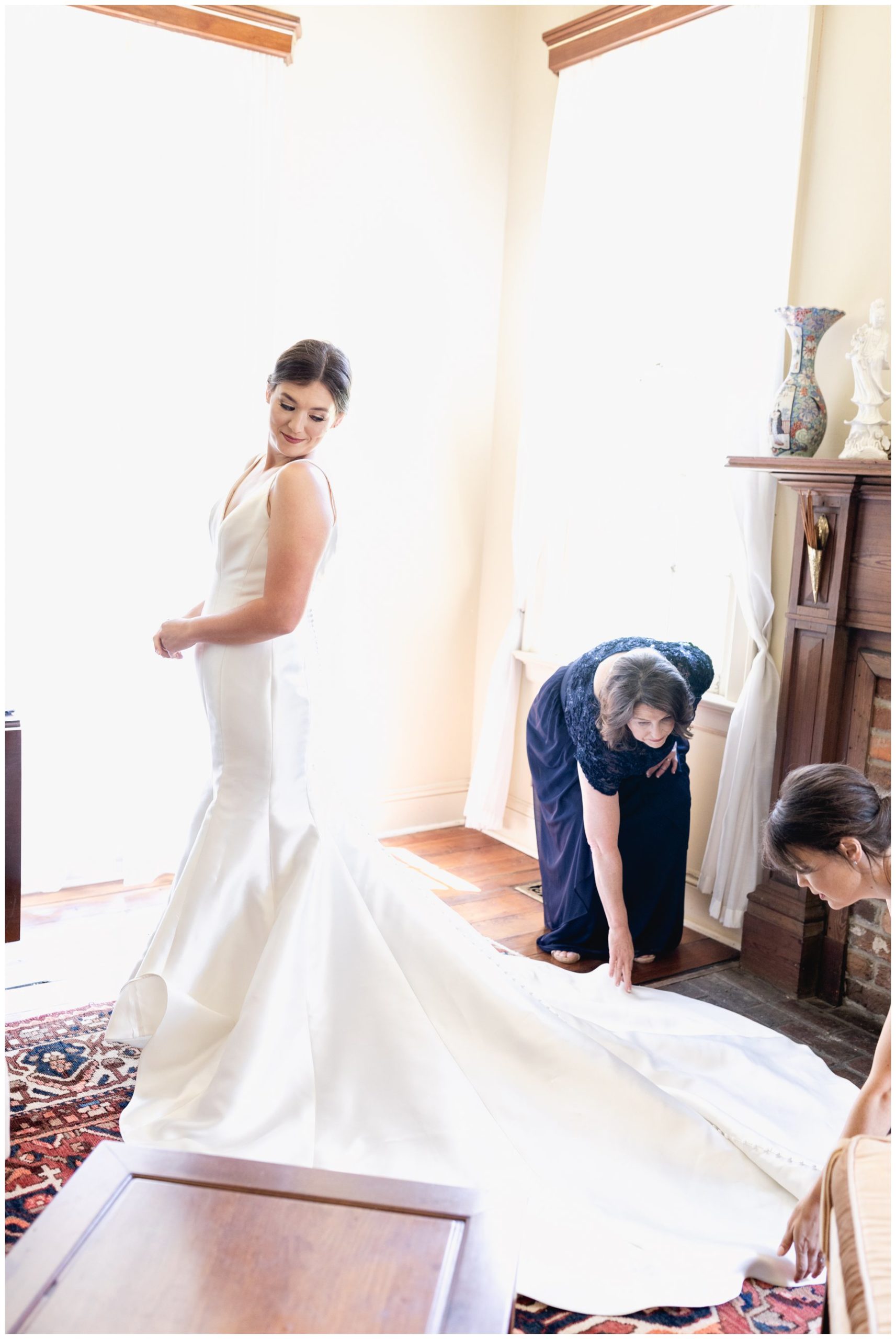 mother of bride and matron of honor helping put on dress,