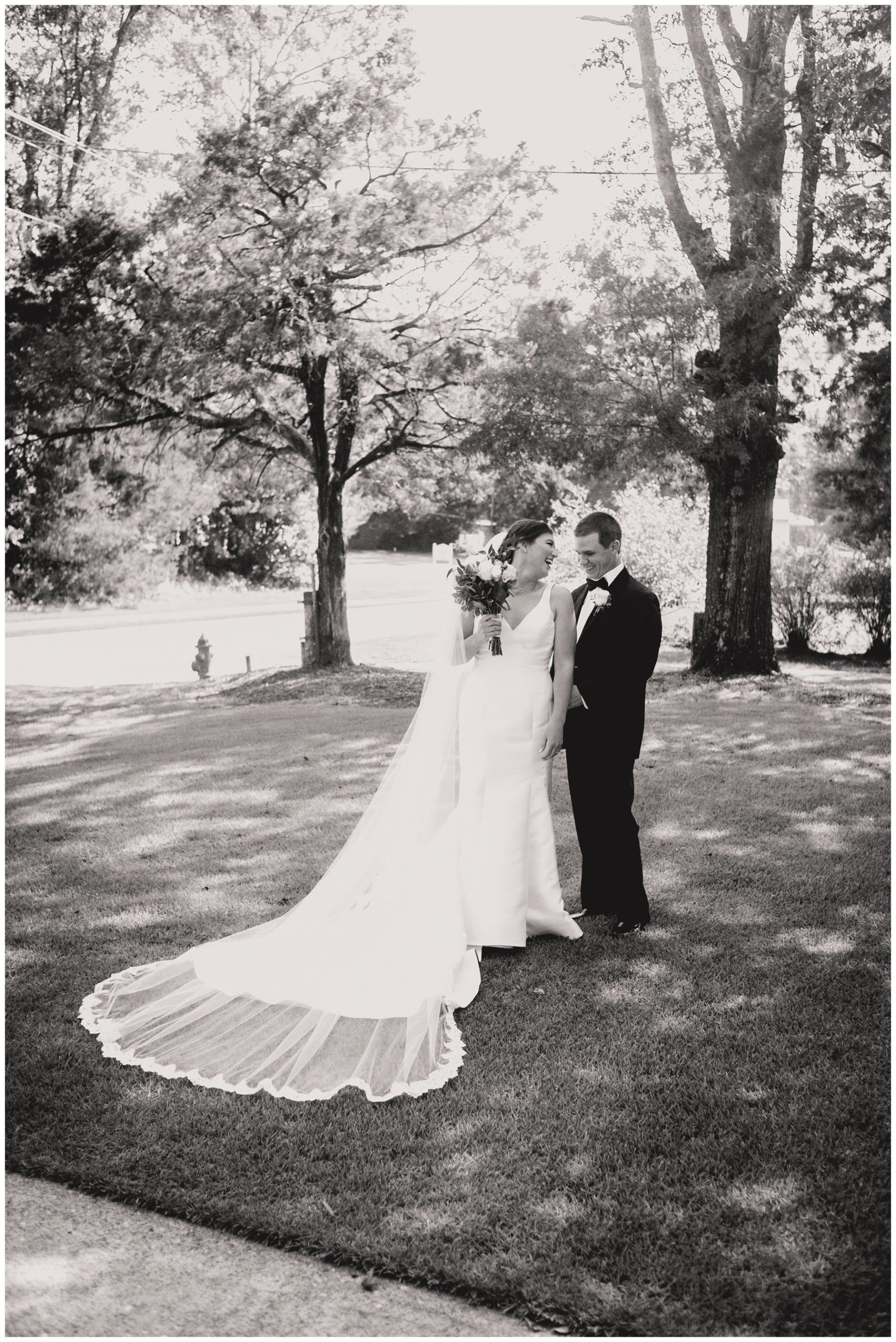 black and white of groom admiring bride's dress,