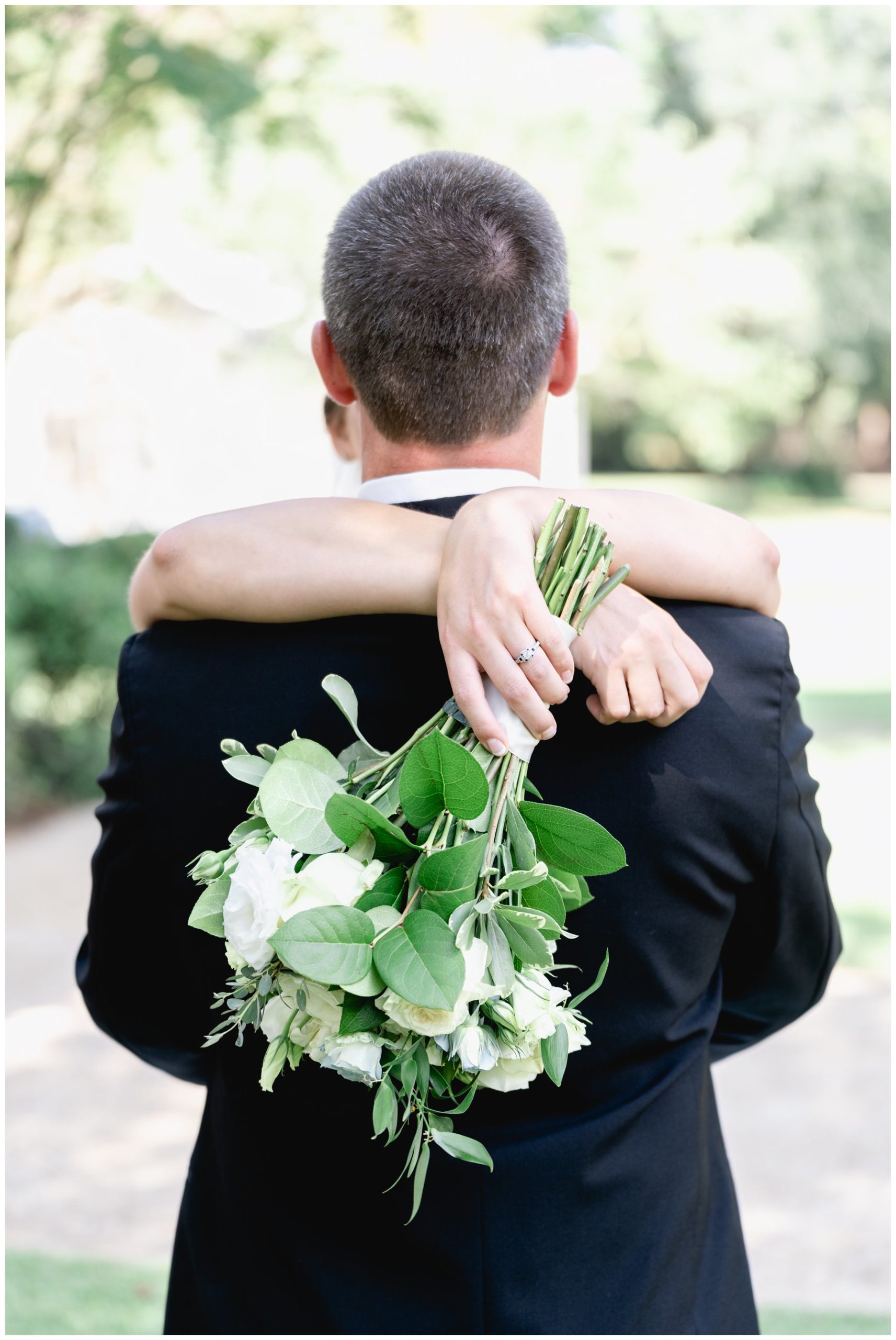 white flowers wrapped aroudn groom's back,