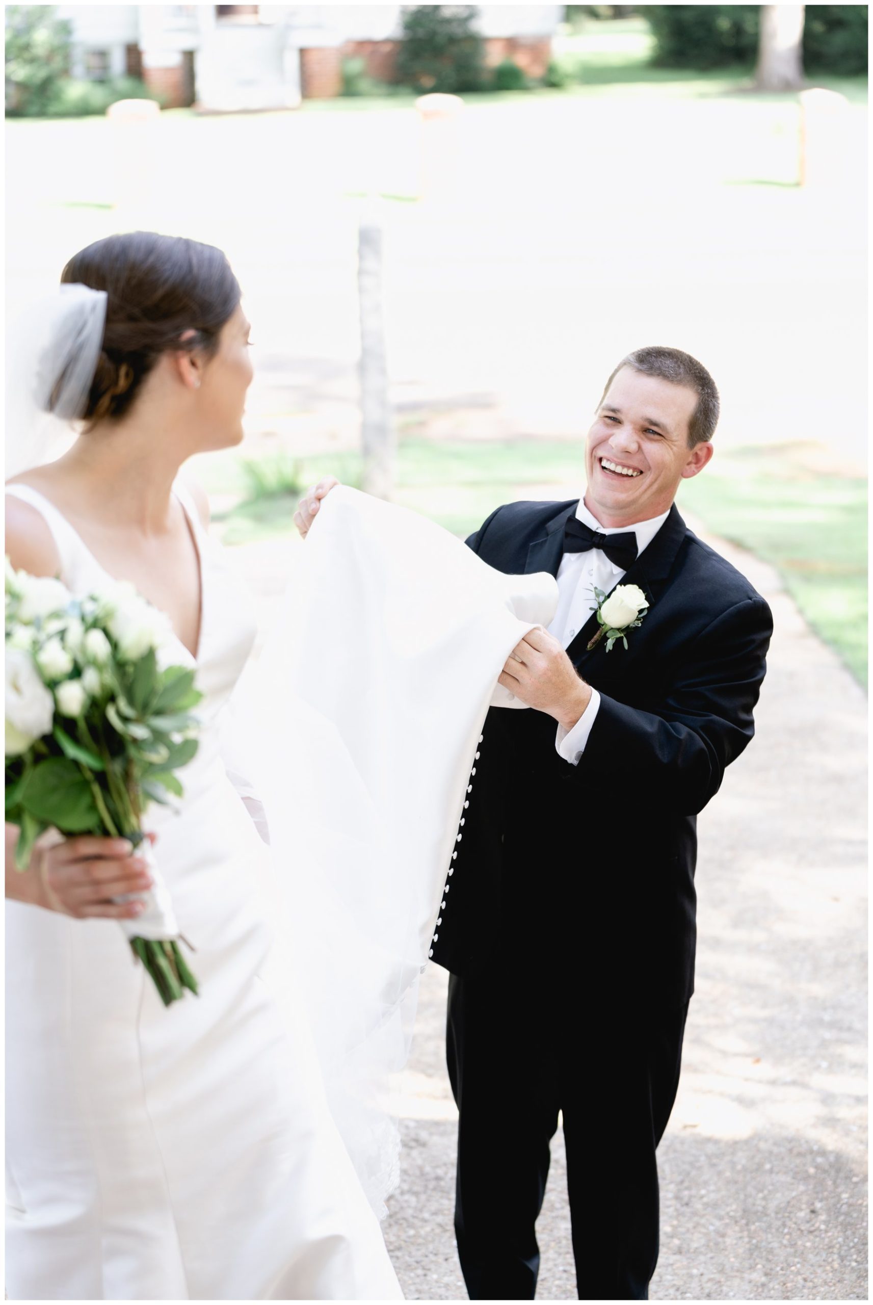 groom helping carry bride's dress,