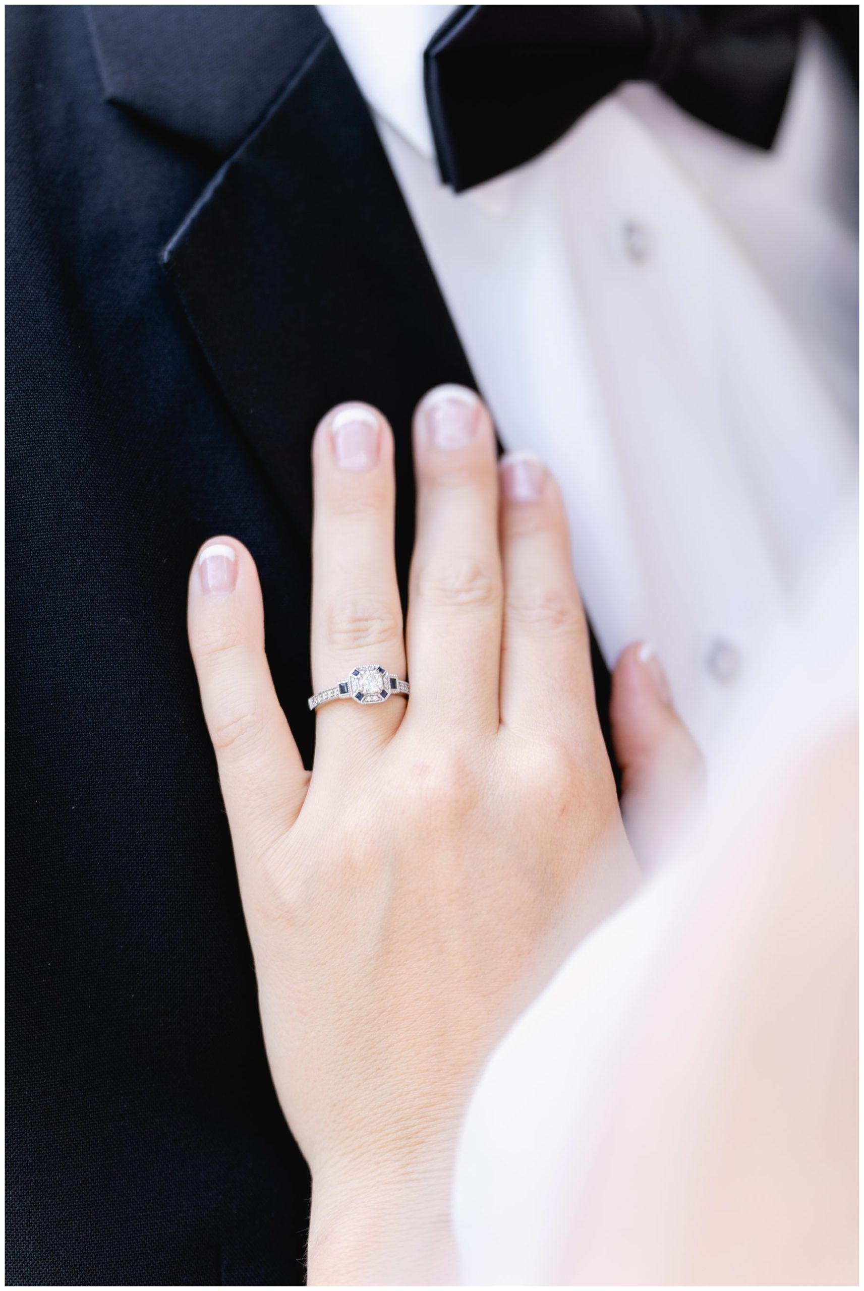 close up of bride's ringed hand on groom's chest,