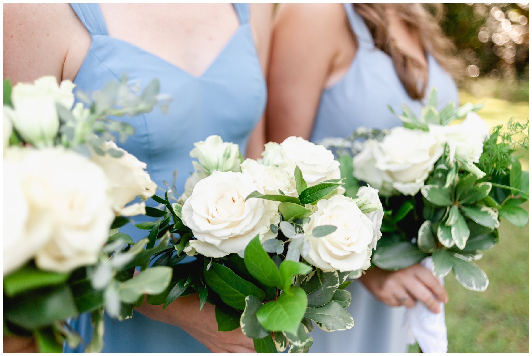 close up of bridesmaids wearing blue dresses holding white flowers,