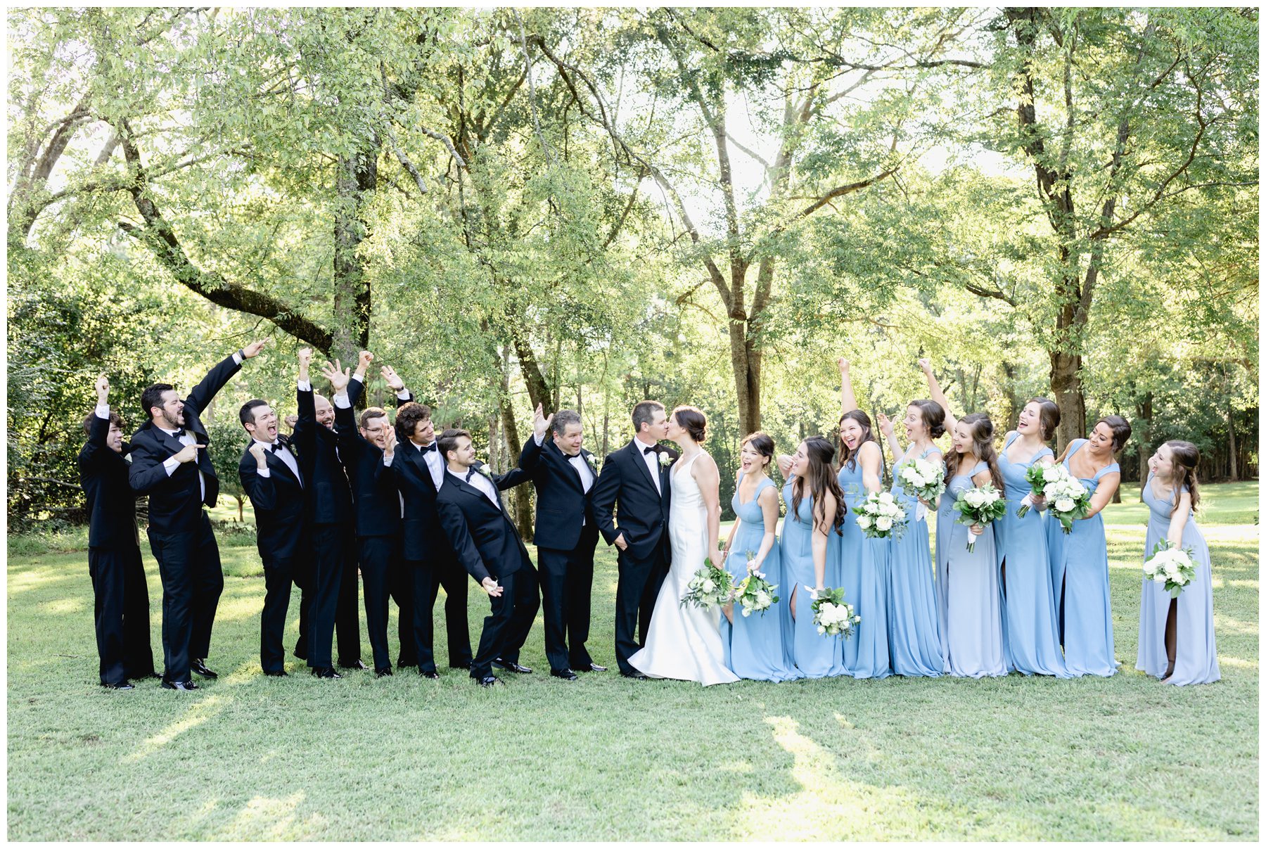 celebrating wedding party while bride and groom kiss each other,