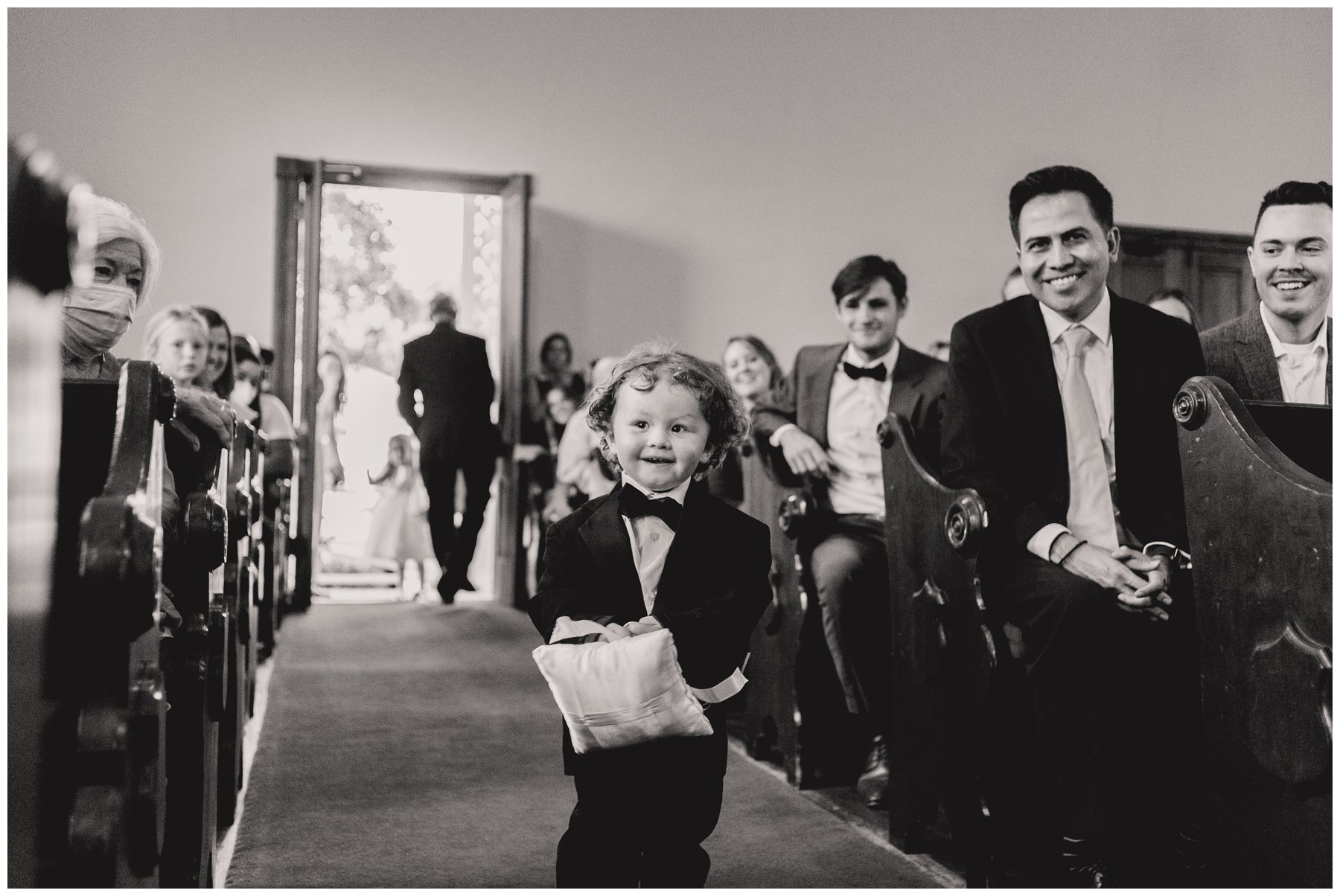 black and white of ring bearer running down aisle,