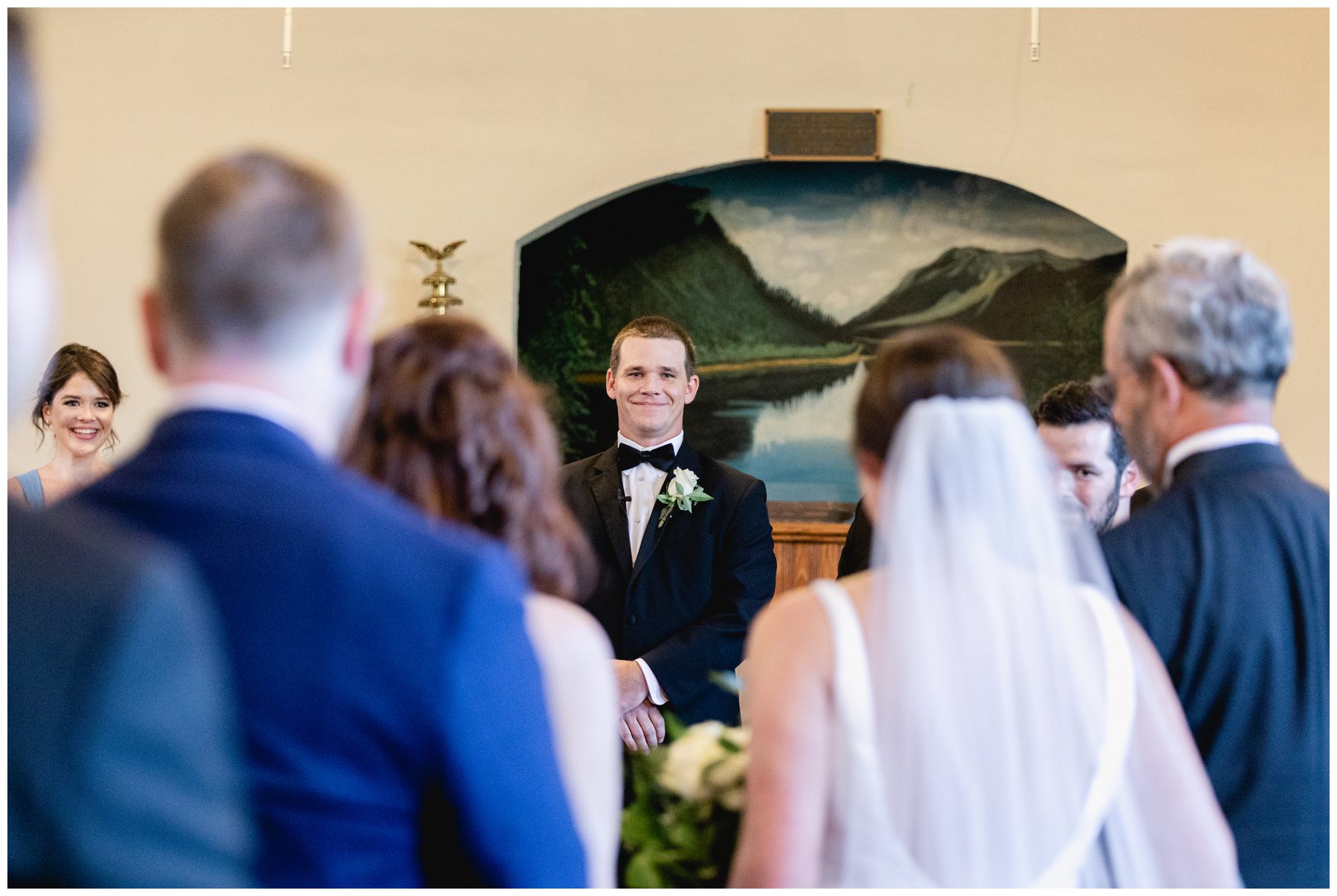 groom smiling at bride while she walks down aisle,