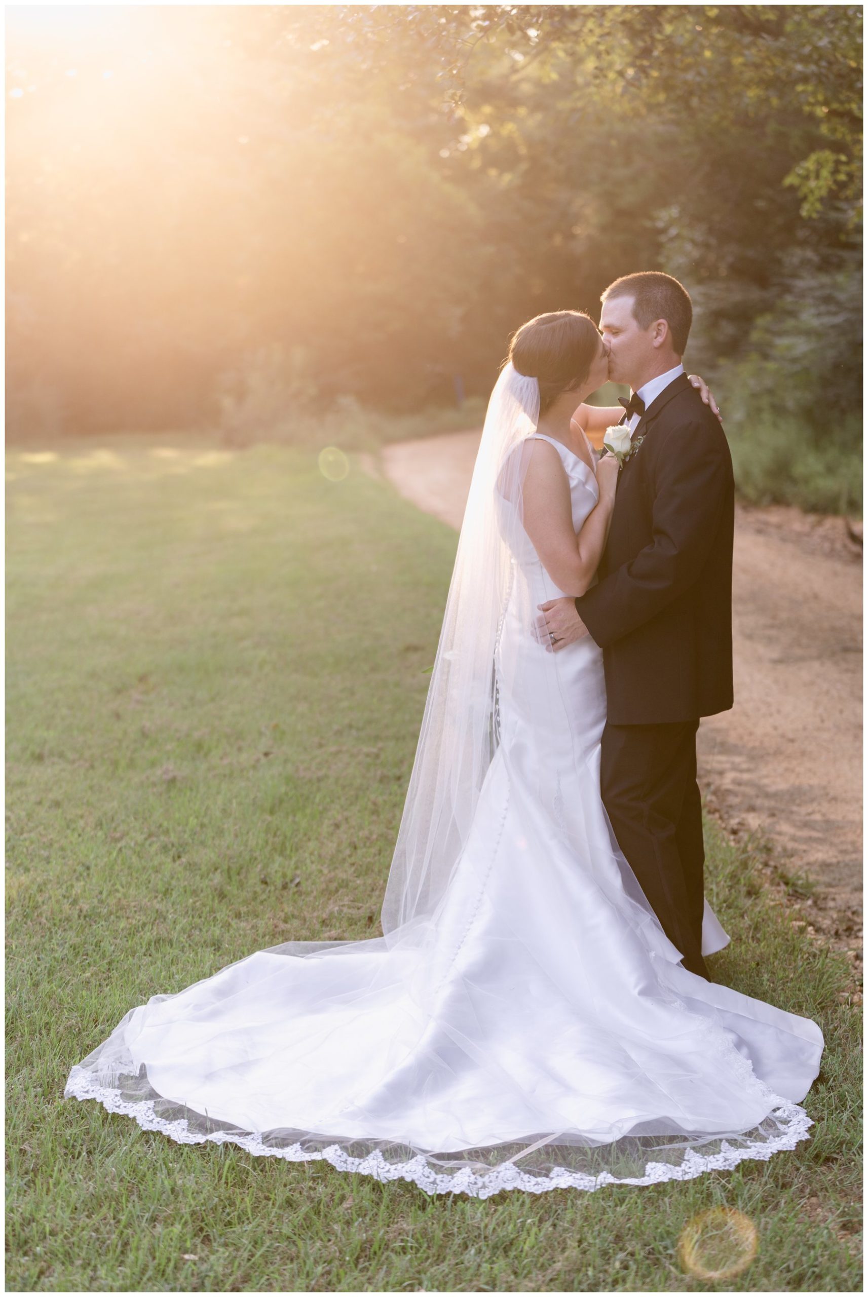 bridea and groom kissing with sunset in background,