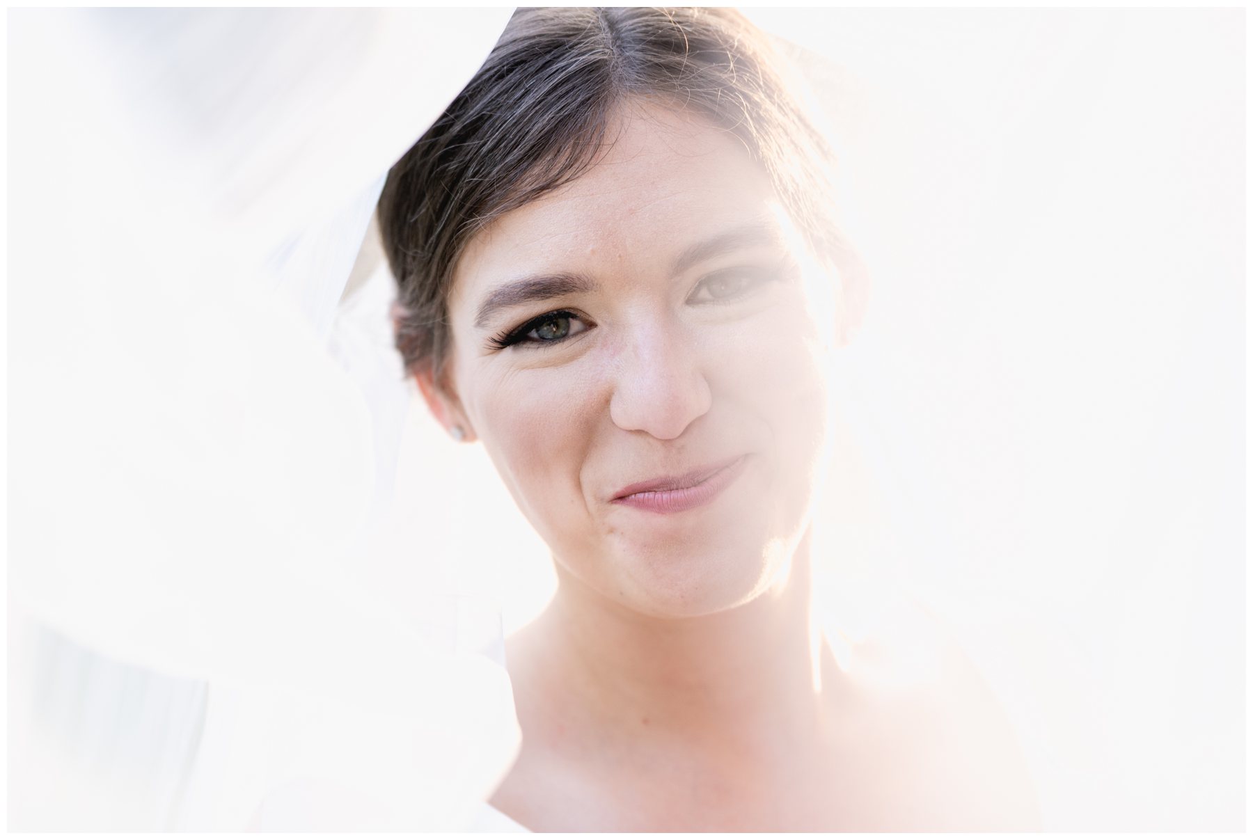 bride smiling with veil over her head,