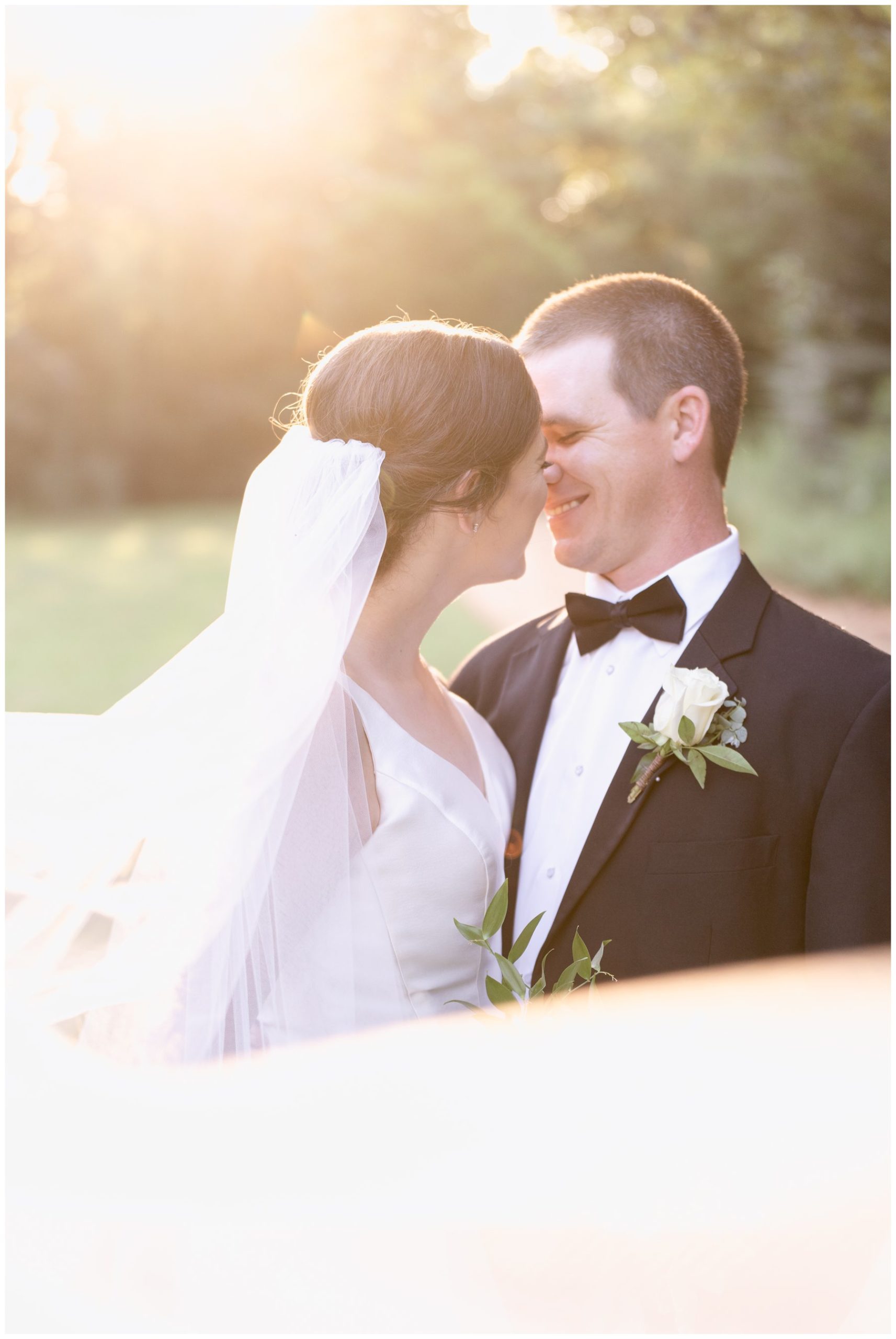 bride and groom almost kissing with sunset in background and veil filling foreground,