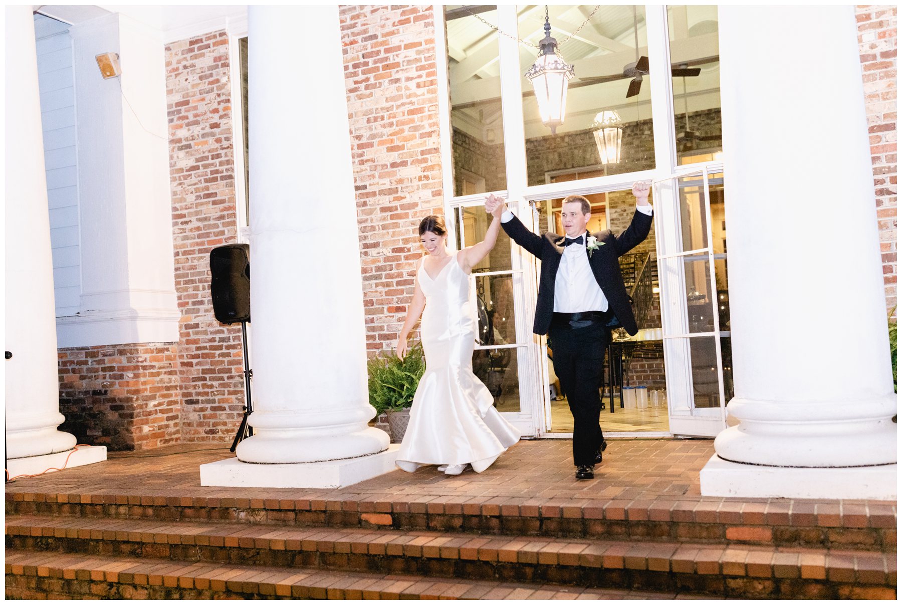 bridea and groom walking past columns towards brick steps to be announced at wedding reception at Merango House,